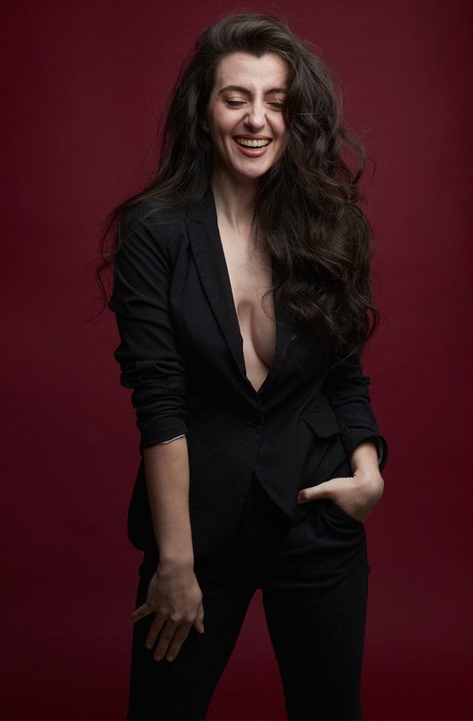 Carmen Tur riendo, traje negro, fondo rojo