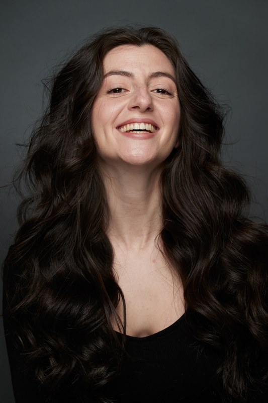 Carmen Tur sonriendo, top negro, fondo oscuro